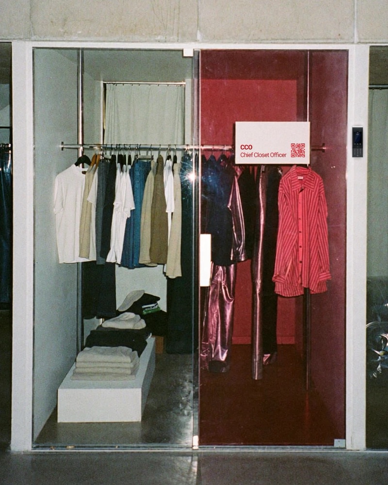 A glass office closet, half clear and half red, with rails of shirts and trousers under a sign that reads CCO, Chief Closet Officer.